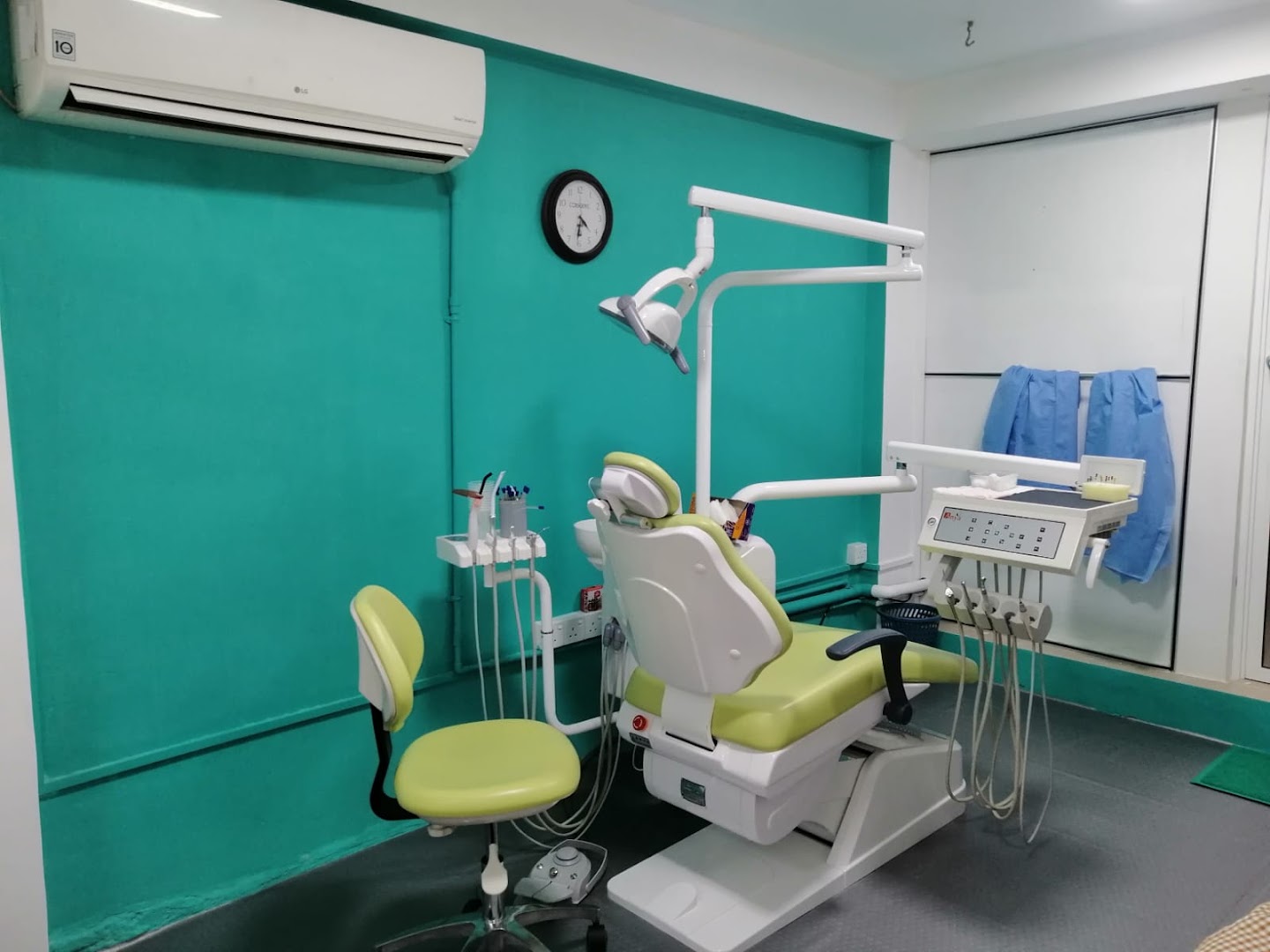 Turquoise treatment room with a dental chair and clinical equipment